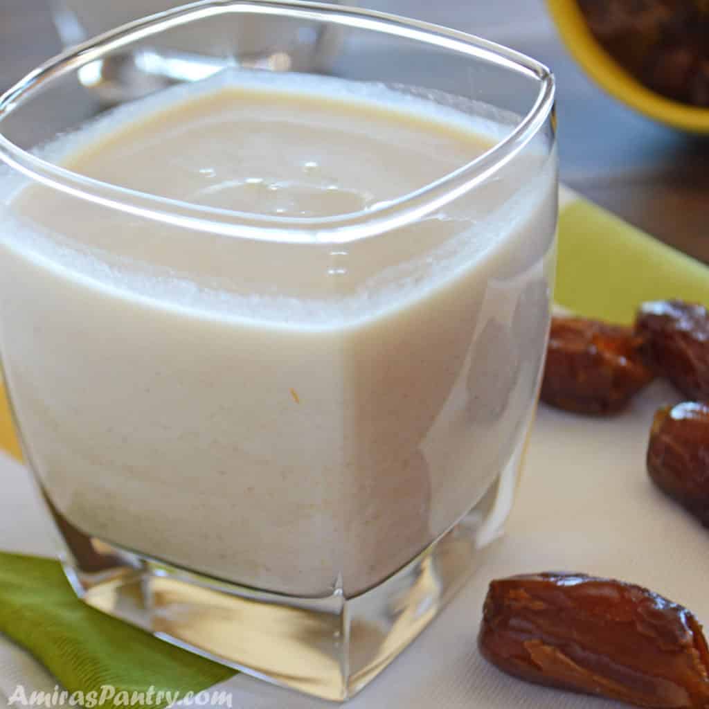 A cup of healthy date shake with some dates on a white and green napkin