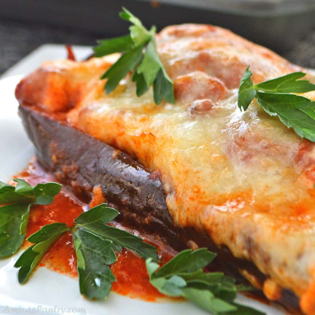 An eggplant boat topped with melted cheese and garnished with parsley.