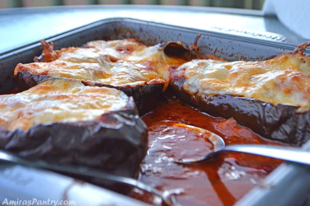 eggplant boats in a baking dish with tomato sauce.