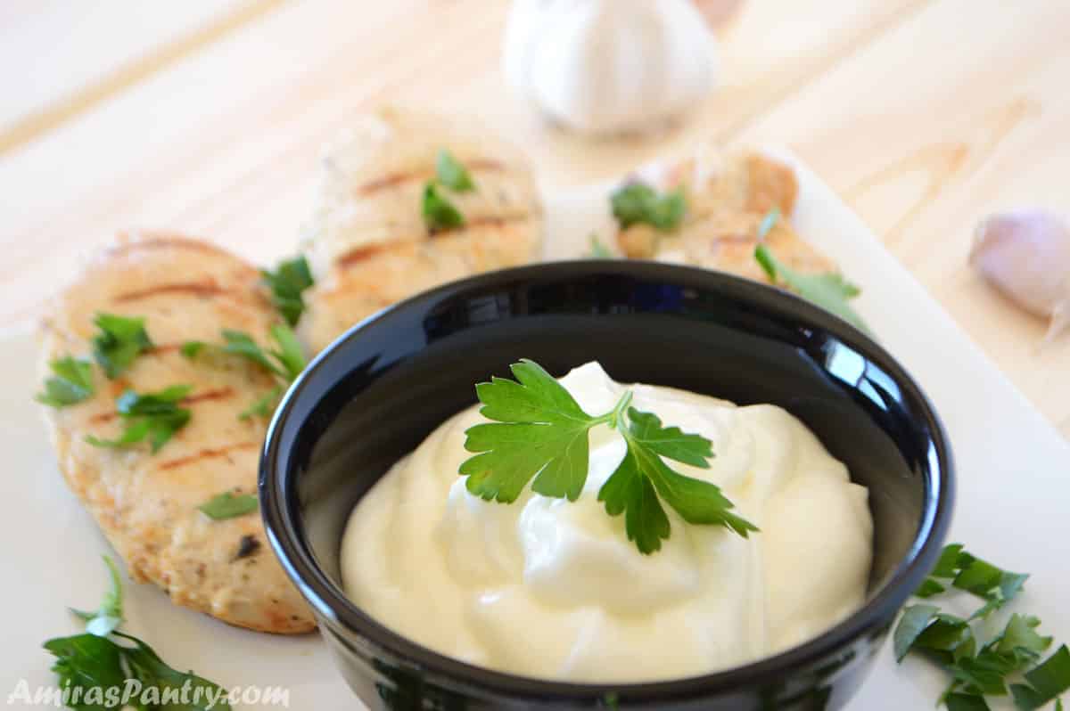 Garlic dip in a bowl with grilled chicken.