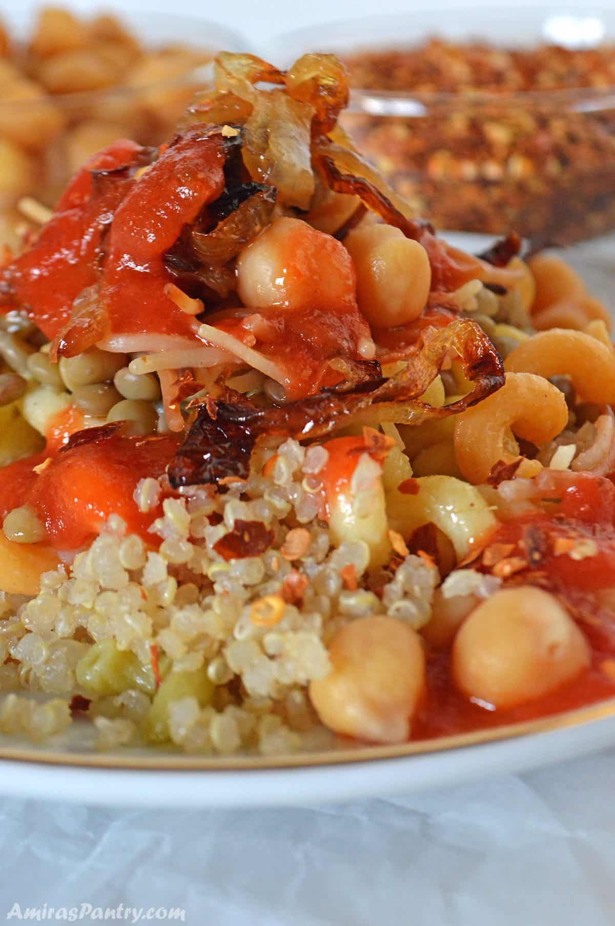 A pile of koshari made with quinoa placed on a white plate