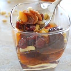 A spoon scooping some of thr dried fruits of a khoshaf cup