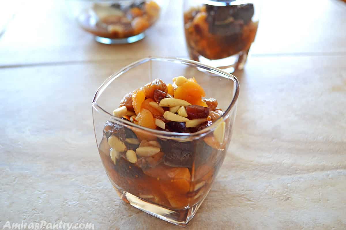 A cup of dried fruits compot placed on a tile table