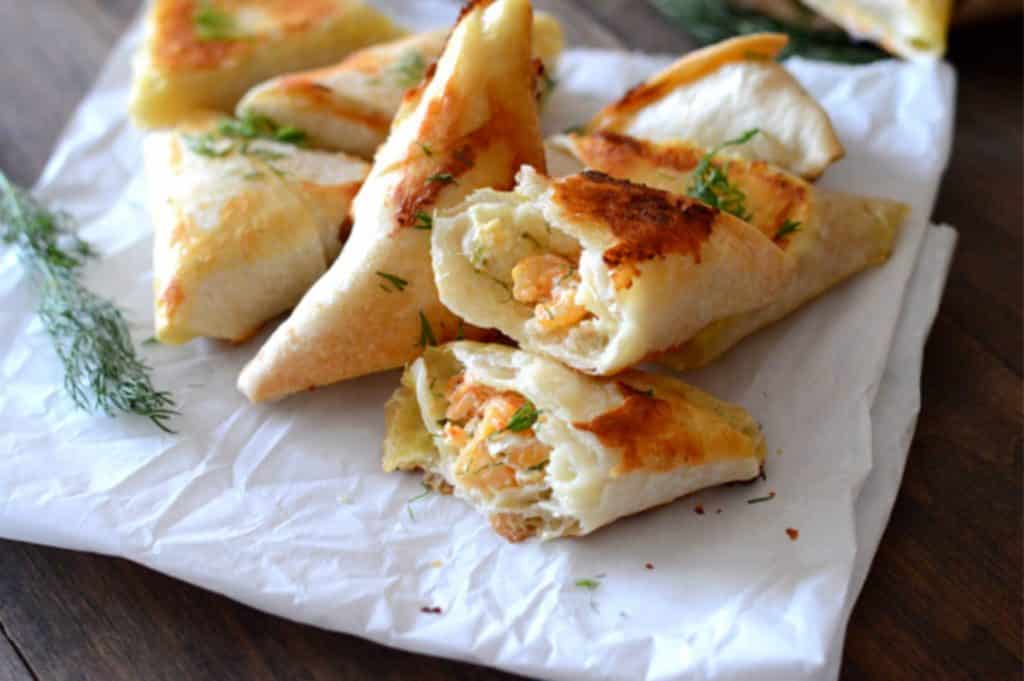 samosas on a parchment paper and cut open to show creamy dill shrimp filling