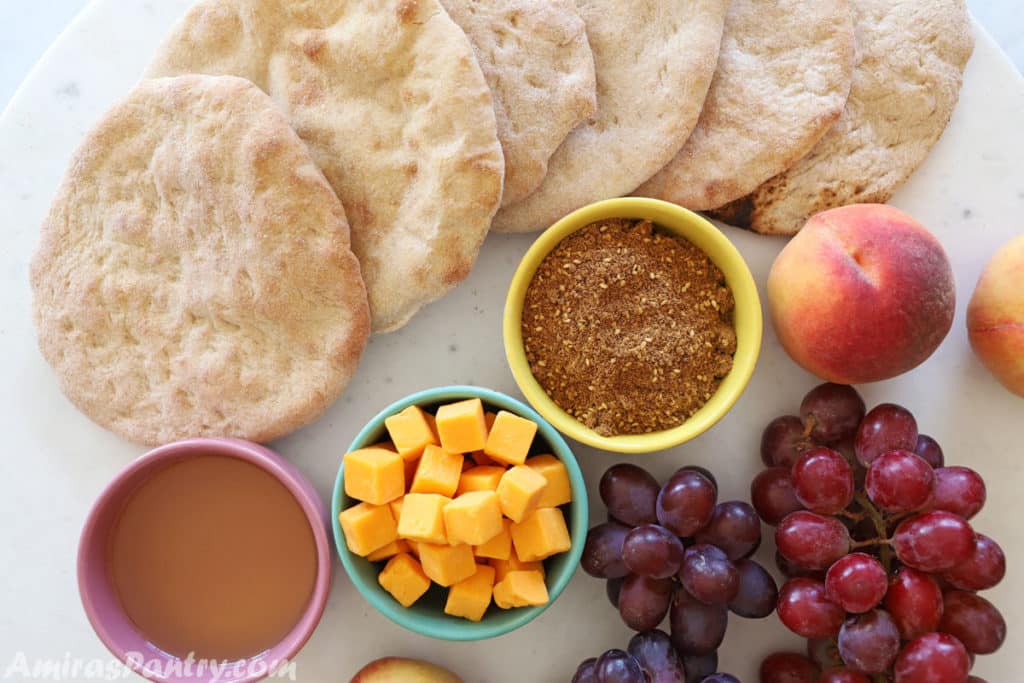 breakfast table with taboon bread, za'atar, olive oil, cheese and fruits