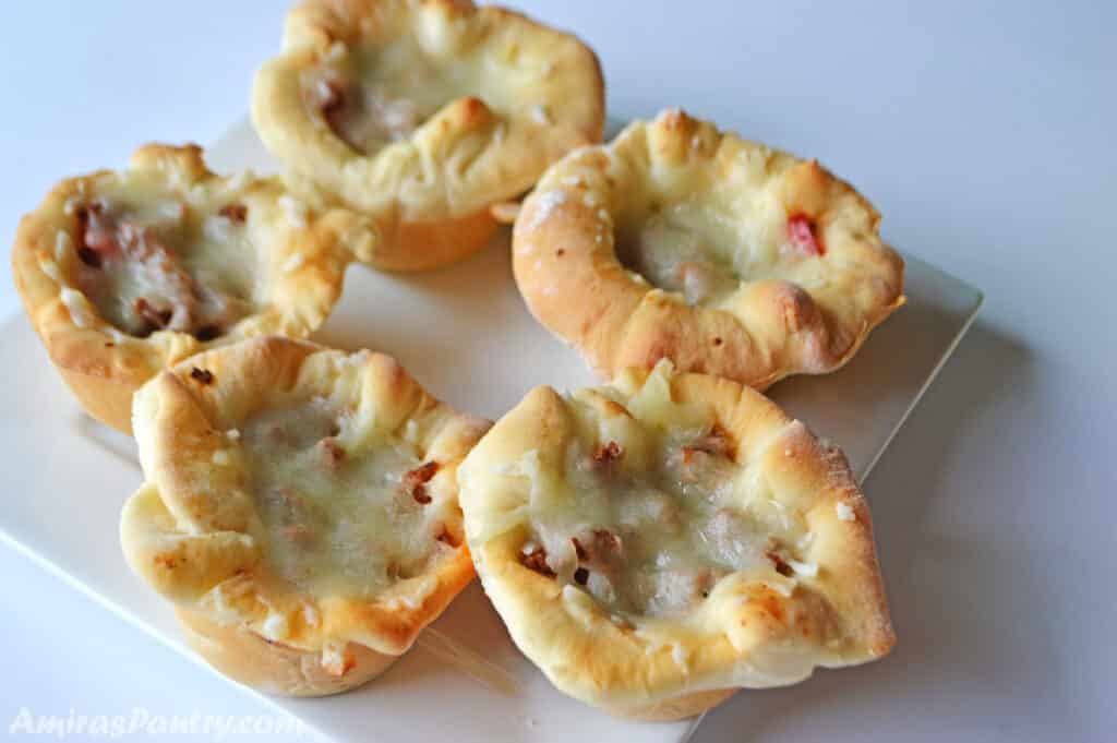 Pizza cups made with the dough and placed on a white square plate