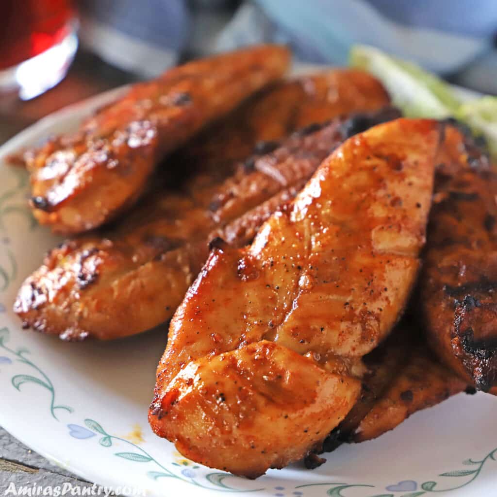 grilled chicken tenders on a white plate with a blur rim.