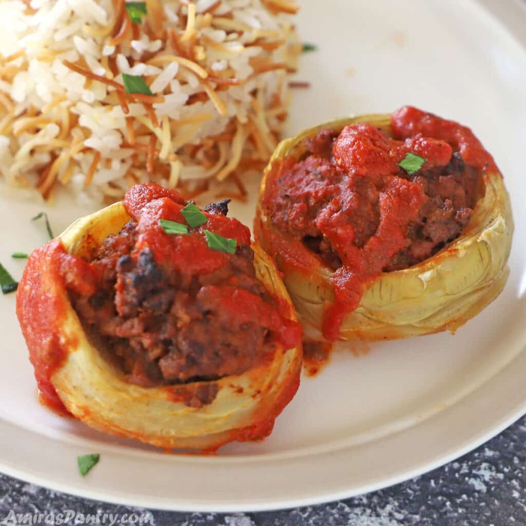 Two artichokes bottoms stuffed with ground beef and placed on a plate with Lebanese rice.