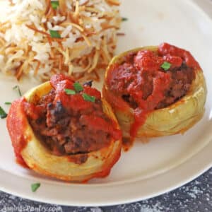 Two artichoke bottoms stuffed with ground beef and placed on a plate with Lebanese rice.