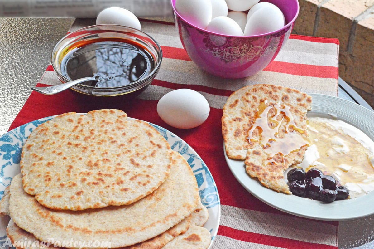 Frühstückstisch mit Eiern, Melasse, Honig, Marmelade und Fladenbrot.