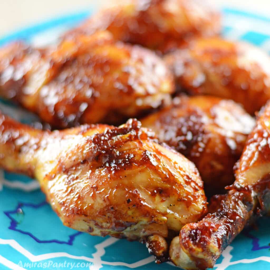 BBq drumsticks on a blue plate placed on a wooden countertop