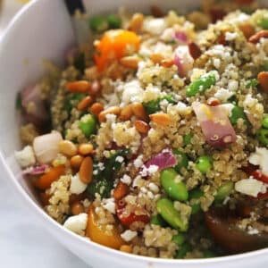 A quinoa veggie bowl with edamame with a serving spoon in it