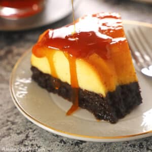 A piece of chocoflan on a white dessert plate with caramel dropping down its side.