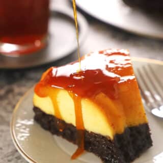 A piece of chocoflan on a white dessert plate with caramel dropping down its side.