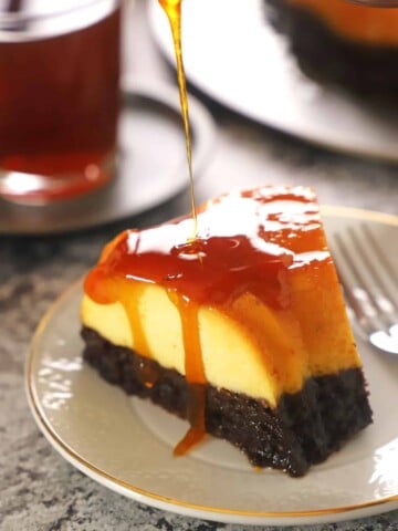 A piece of chocoflan on a white dessert plate with caramel dropping down its side.