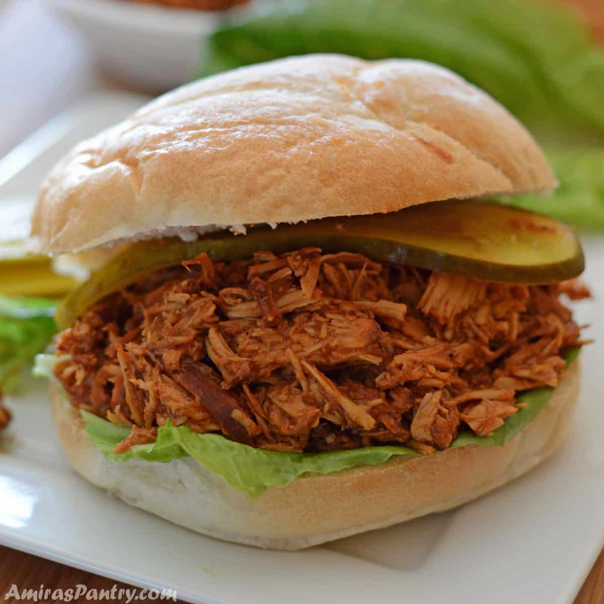 a pulled chicken sandwich on a white plate