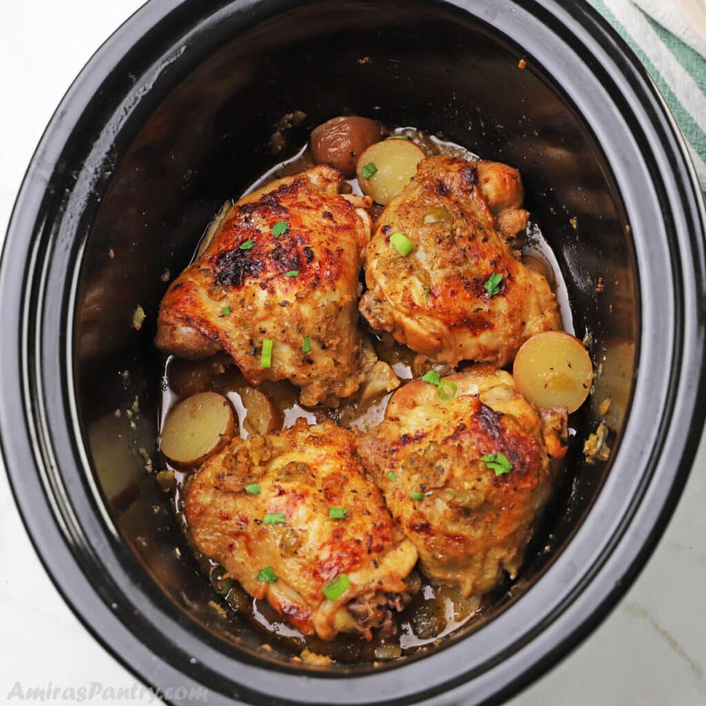 a slow cooker with chicken thighs and potatoes.