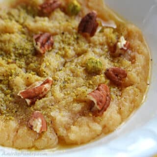 a close up on wheat halwa in a white bowl garnished with some crushed nuts