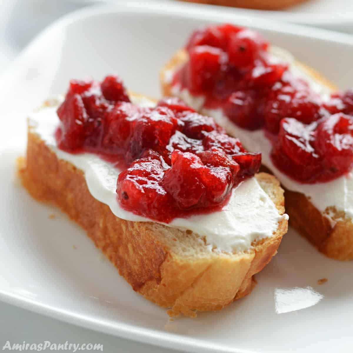 Cranberry sauce spread over toast and placed on a white plate.