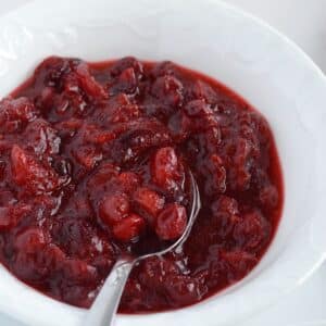 Healthy Cranberry sauce in a white bowl with a spoon in it.