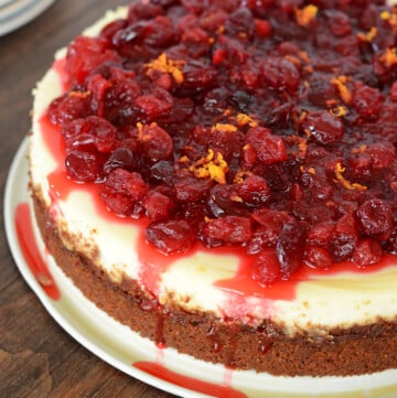 cranberry orange cheese cake on a white plate and placed on a wooden table.