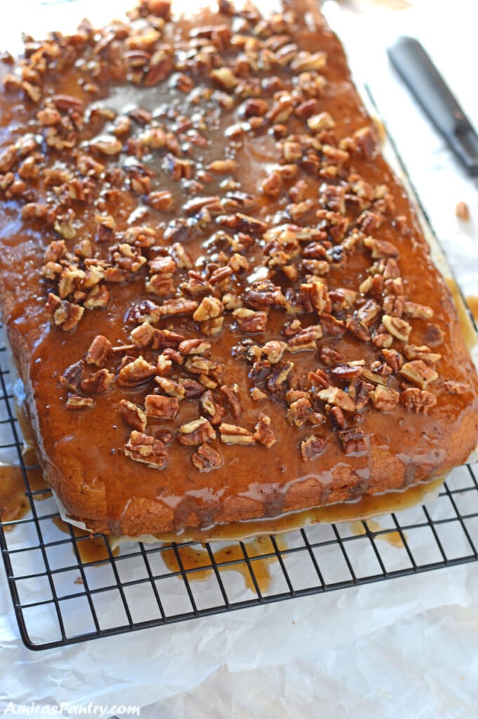 Pumpkin sheet cake on a wire rack dripping butter-pecan sauce.