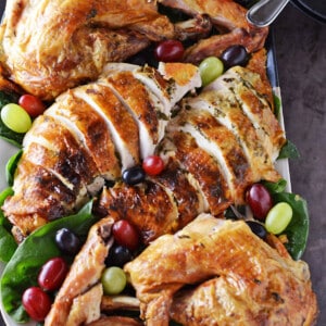 Platter of carved juicy roast turkey decorated with fruits and greens.