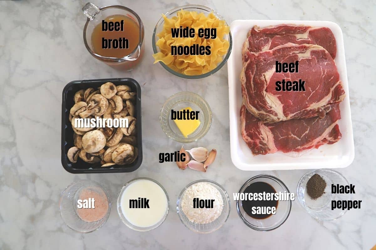 beef stroganoff ingredients on a white marble surface.