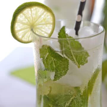 A close up photo of a freshly made Mojito mocktail glass garnished with lime slice and fresh mint leaves.