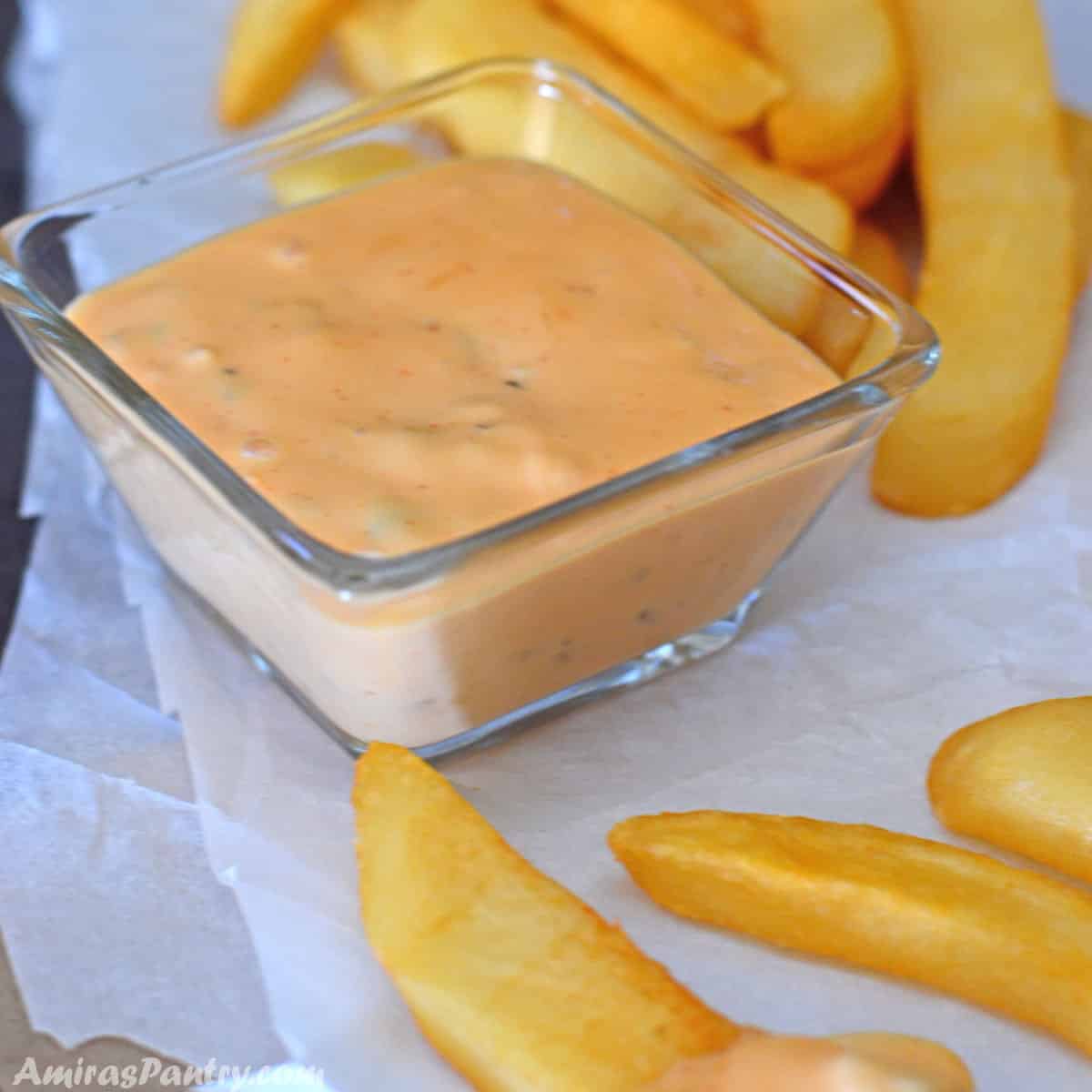A small condiment bowl with big mac sauce with some fries.