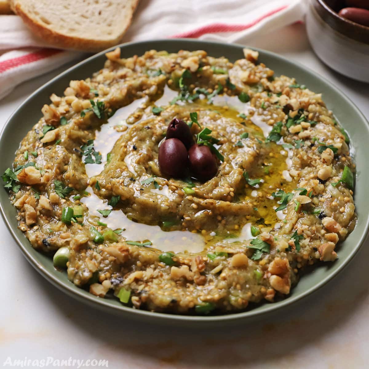 Greek eggplant dip placed in a green plate and garnished with parsley and olive oil.