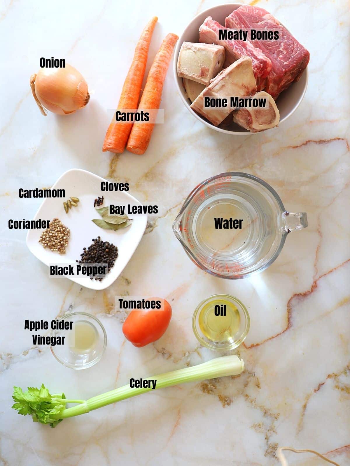 Ingredients to make bone broth on a white marble table.