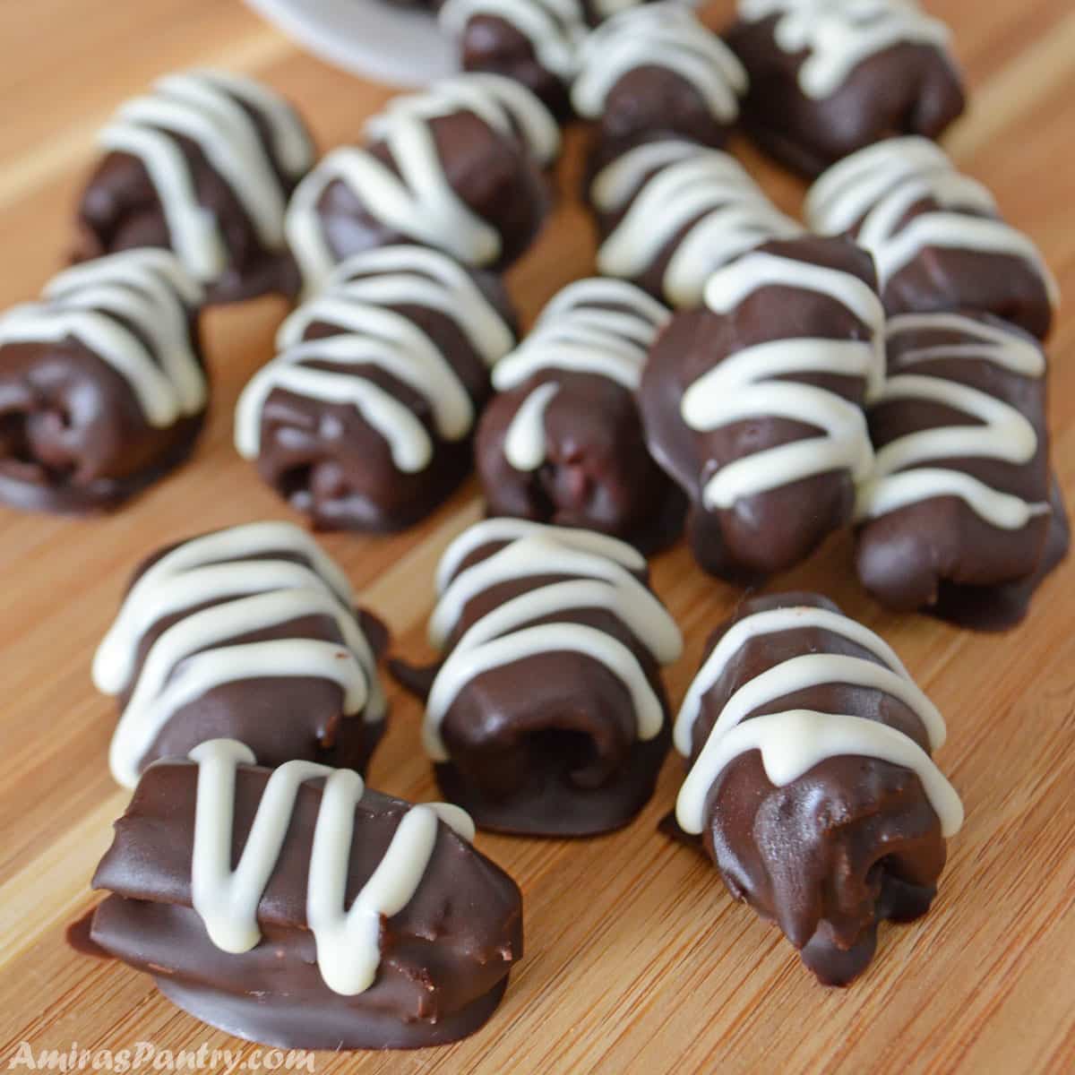 Chocolate covered dates scattered on a wooden surface.