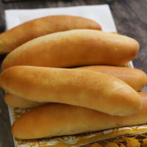 A stack of hot dog buns placed on a kitchen towl.