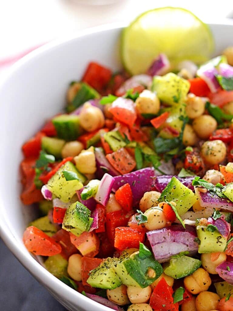 A close up image of a white serving bowl of chickpea salad.