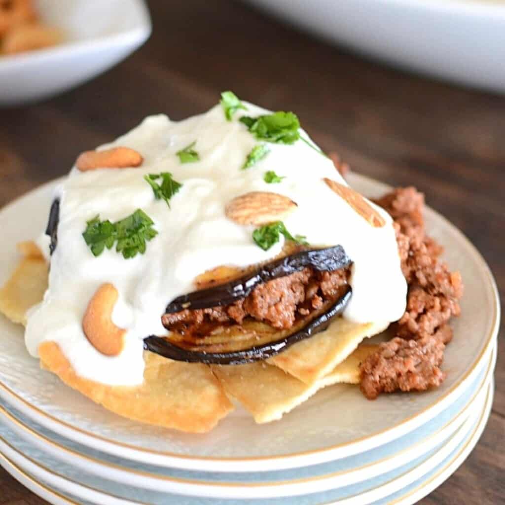 Eggplant maqdous on a white plate with yogurt sauce.