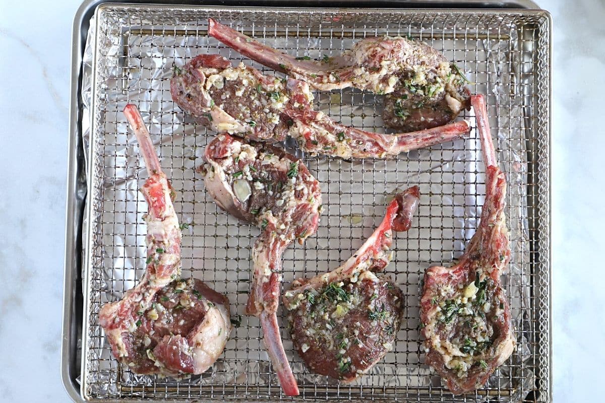 Marinated lamb chops placed on the air fryer basket.