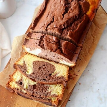 An overhead view of a sliced marble pound cake placed on a wooden cutting board.