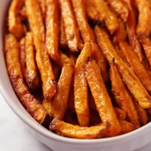 A close up look on a white serving plate with sweet potato fries.