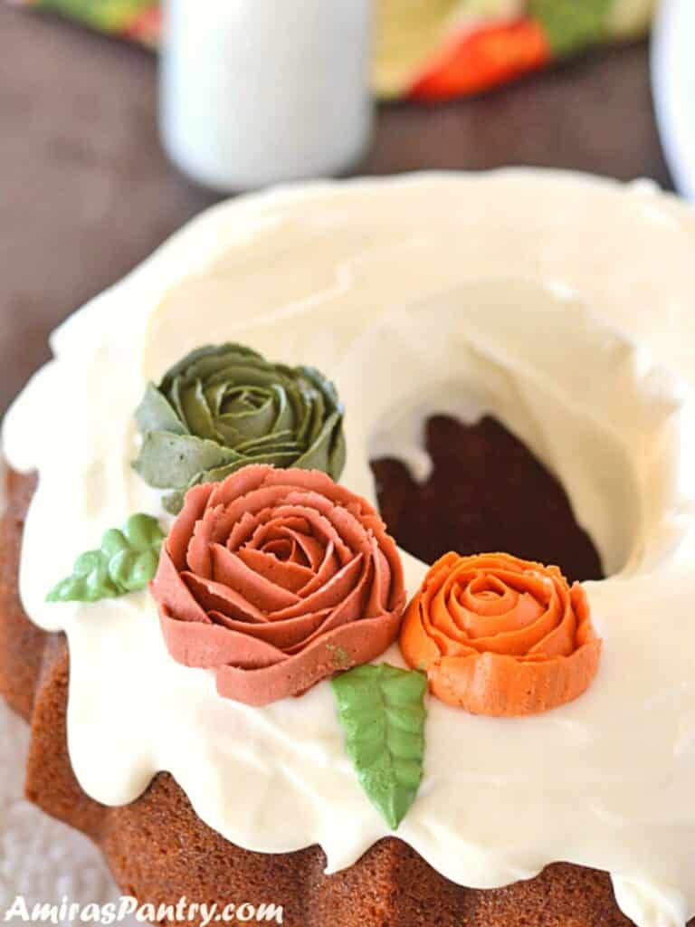 A top view of pumpkin bundt cake on a white platter with a bottle of milk in the back.