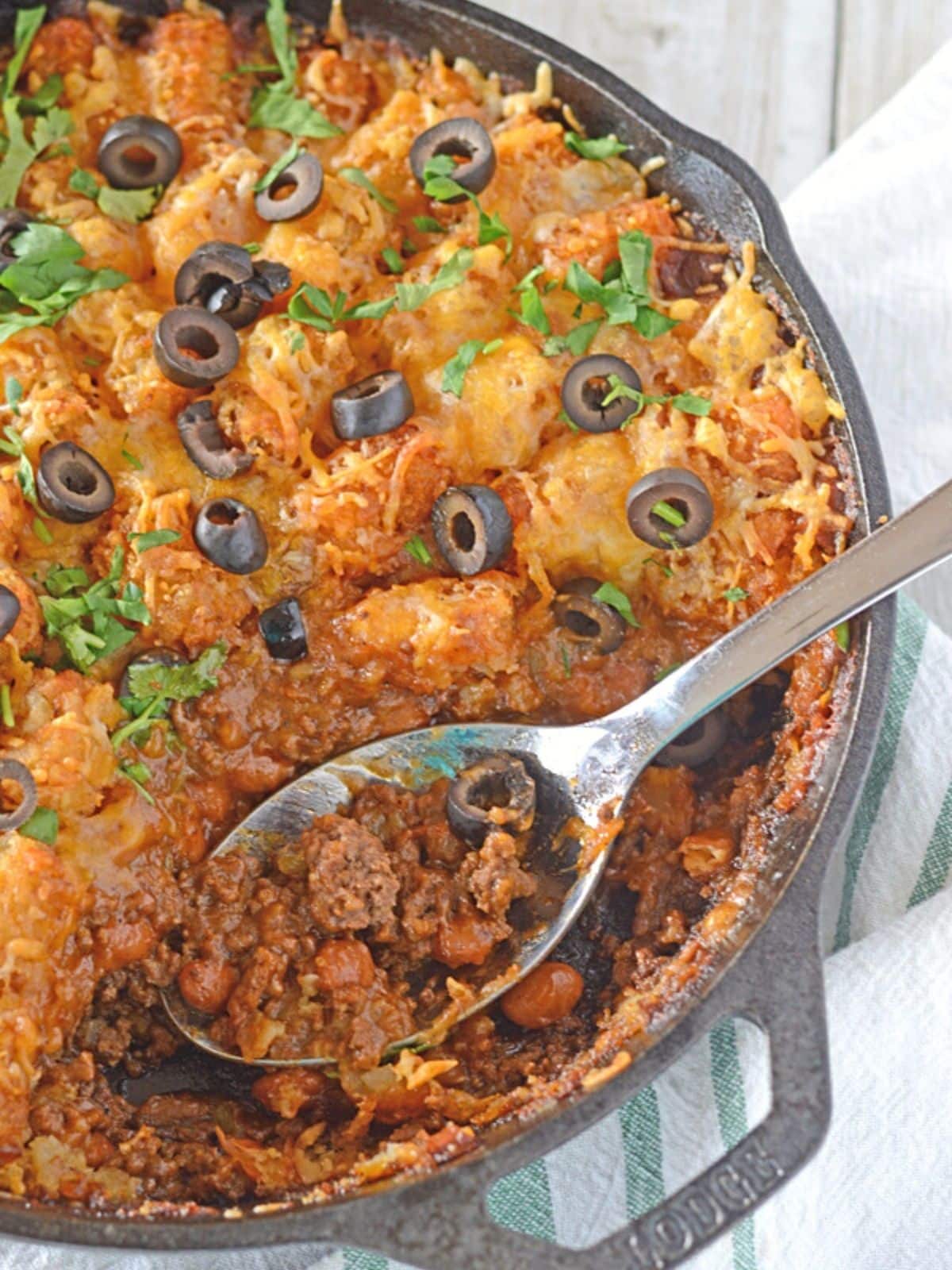 A bird's eye image of a taco tater tot casserole with a spoon in it.
