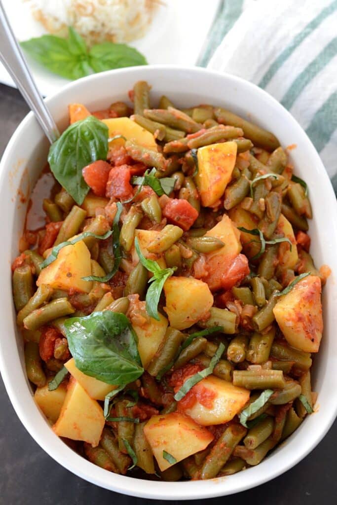 Overhead view of a white serving dish with green beans and potatoes.