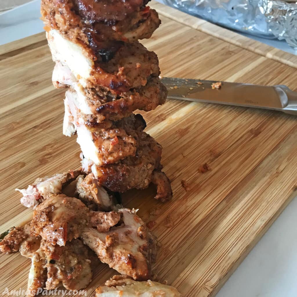 Carving Chicken Shawarma meat on a wooden surface.