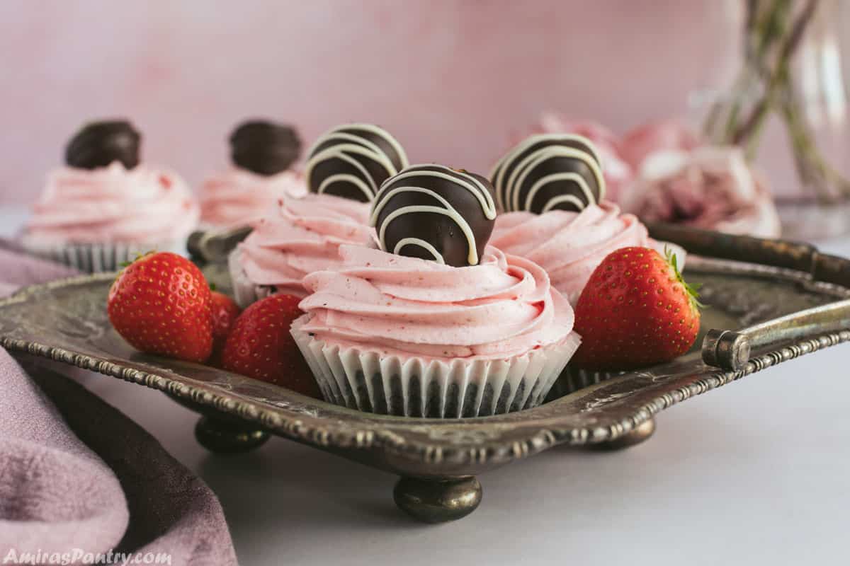 Chocolate cupcakes decorated with chocolate covered strawberries and placed on a metal serving tray.