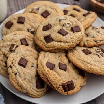 A zoom in image of chunky chocolate chip cookies on a white plate.