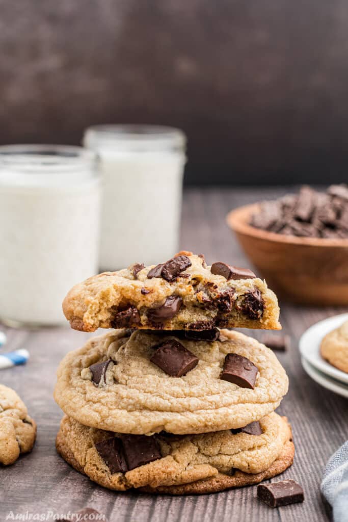 A stack of chocolate chip cookies with a bite taken from the top one.