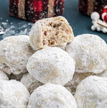 A pile of snowball cookies with a bite taken from one to show texture.