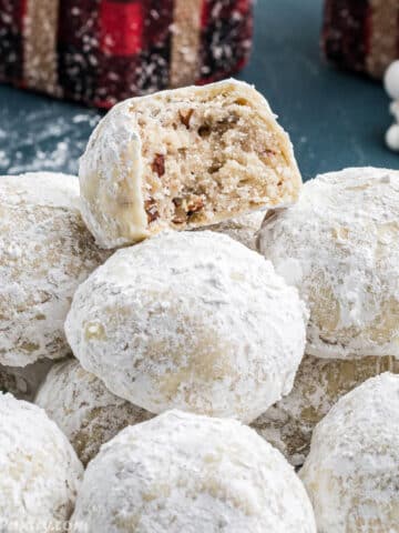 A pile of snowball cookies with a bite taken from one to show texture.