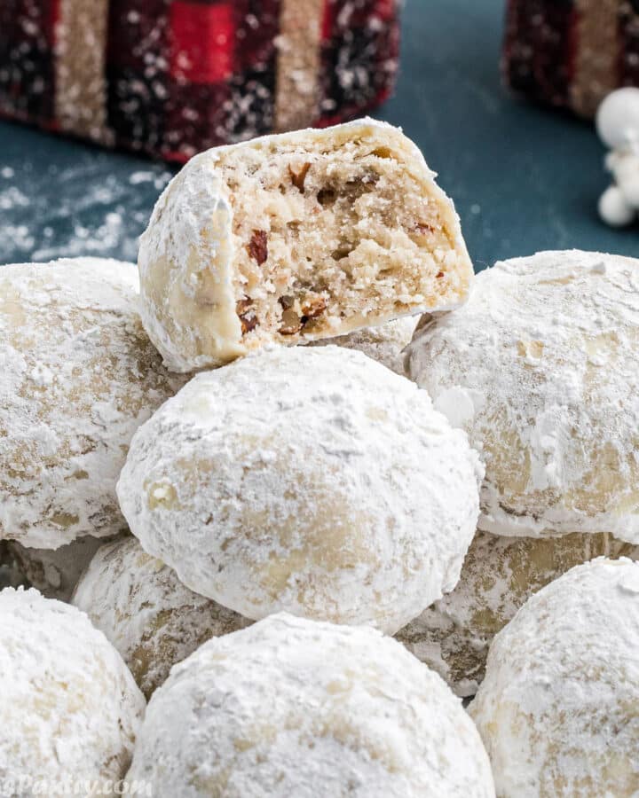 A pile of snowball cookies with a bite taken from one to show texture.