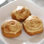 Three frosted sweet potato cookies on a small white dessert plate.